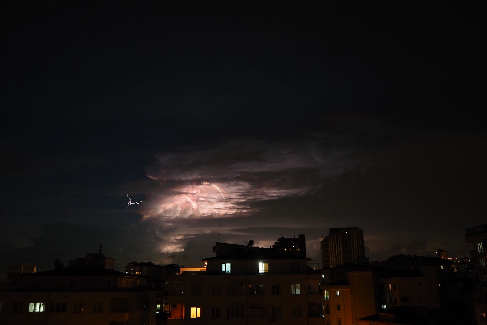 Gece kent silueti üzerinde şimşekli fırtına